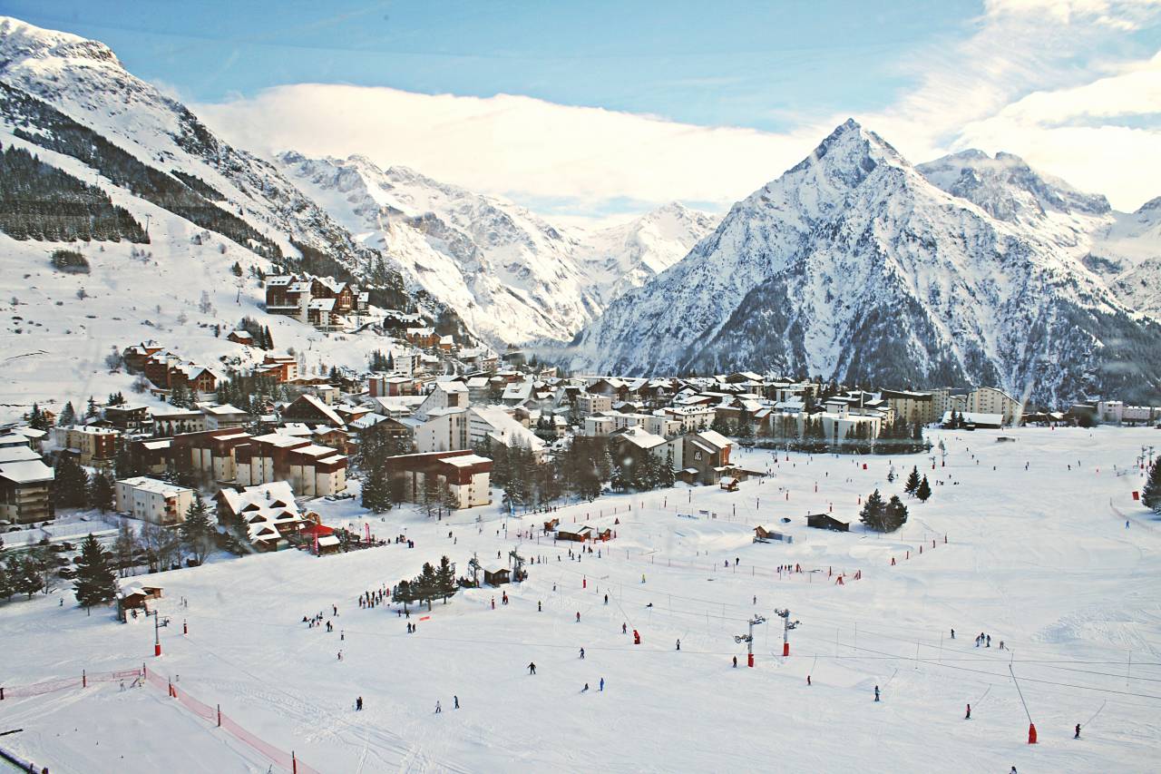 buildings, houses, mountain, landscape, winter, snow, cold, people, crowd, ice, skating, trees, kids, men, women, transmission, line, net, sky, clouds
, 