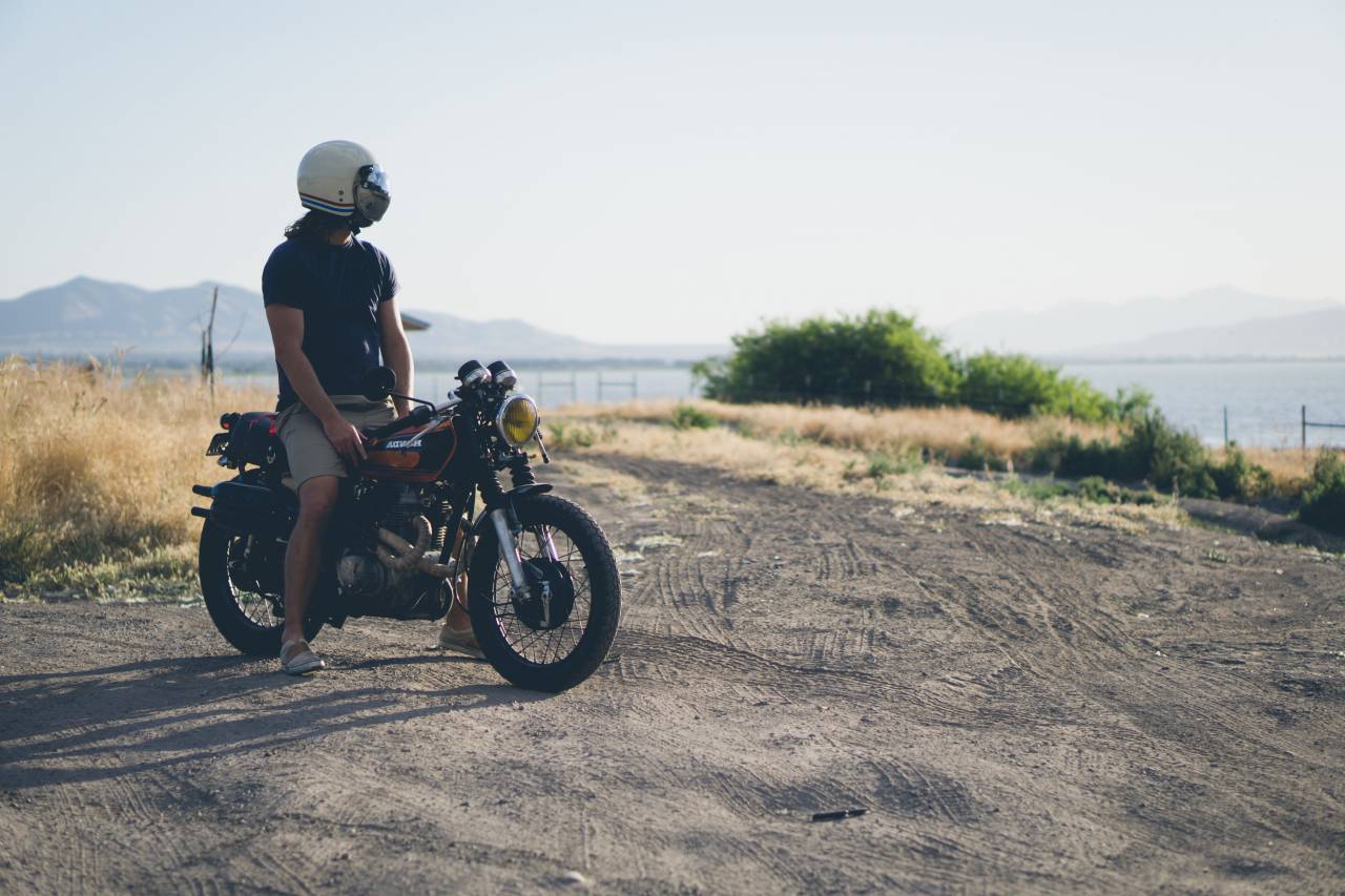 people, man, alone, helmet, motorcycle, travel, field, grass, sea, water, mountain, sunny, day, sky, clouds
, 