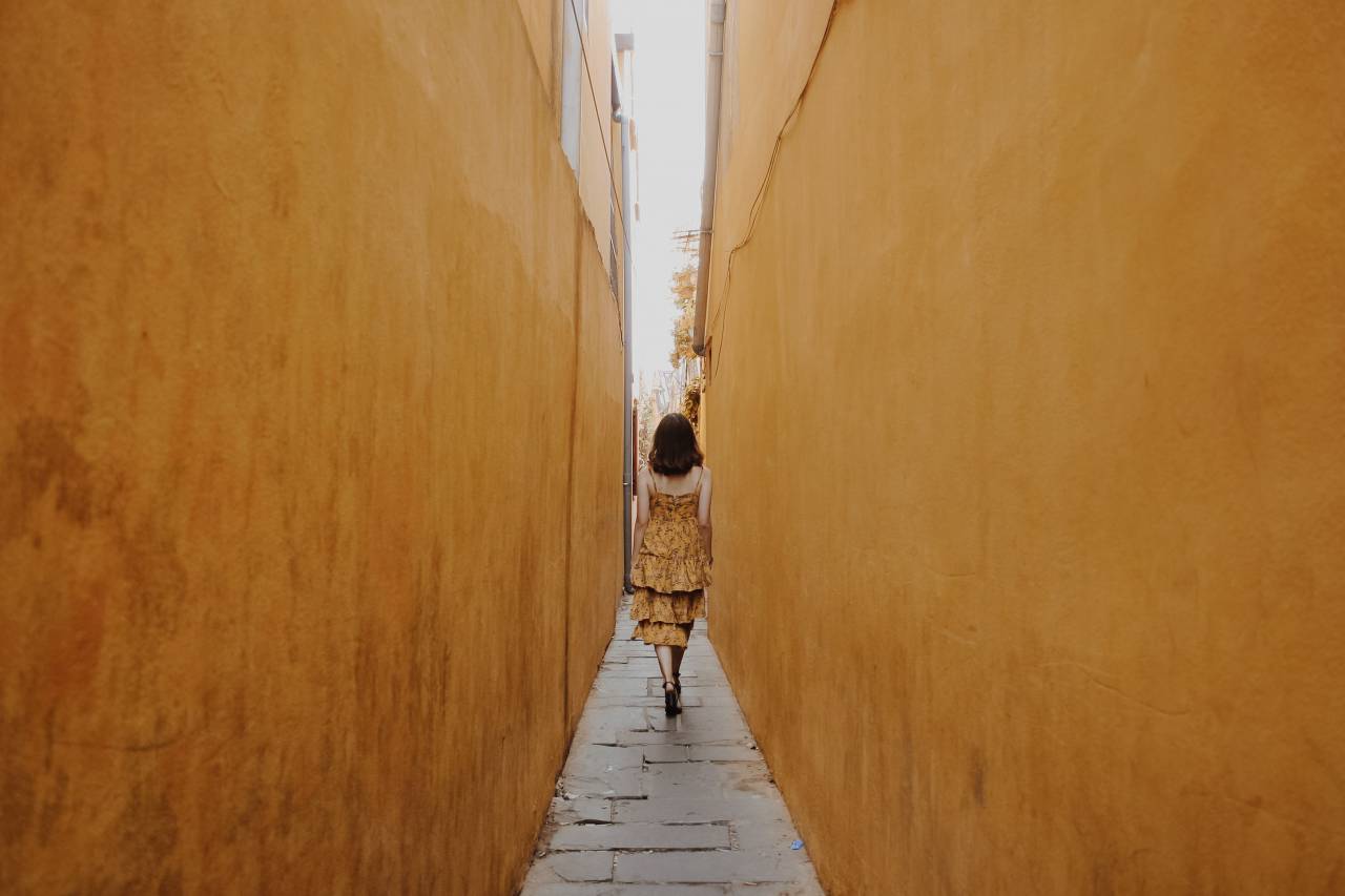 woman;yellow dress;corridor;narrow,women,outdoors,lifestyles,one person,men,walking,adult,architecture,summer,caucasian ethnicity, 